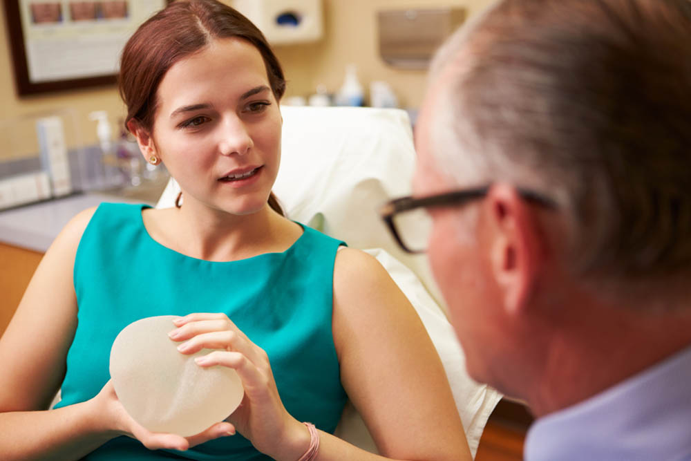 Young woman discussing about breast implants with her surgeon.
