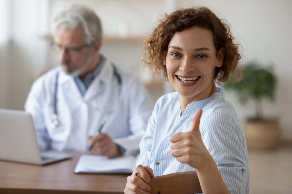 Patient giving thumbs up after discussing surgery with doctor
