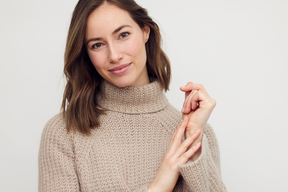 Woman in a turtleneck sweater, embodying the natural look post-brow lift surgery.