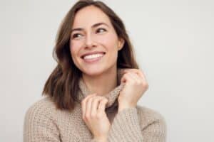 Smiling woman in beige sweater, embodying pre-operative health for surgery.