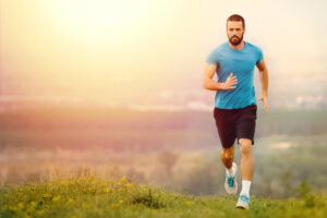 Man in blue shirt jogging in the field exemplifies calf implant benefits.