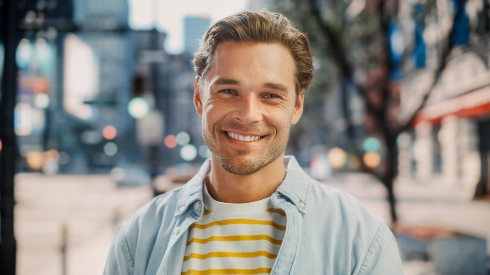 Smiling man in an urban setting, epitomizing the ideal candidate for a masculine forehead lift.