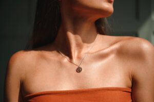 Close-up of a woman's neckline wearing a pendant, symbolizing post-surgery care.
