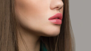 Close-up of a woman's lips slightly parted, highlighted by pink lipstick, demonstrating lip augmentation effects.