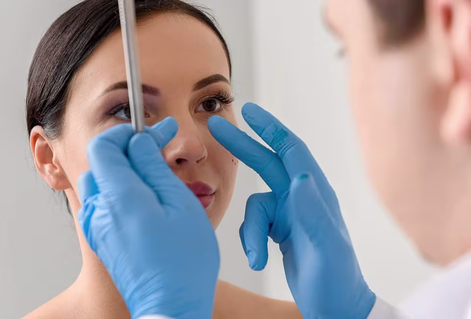 A doctor assessing a patient's nose during a rhinoplasty consultation to discuss aesthetic improvements and functional corrections.