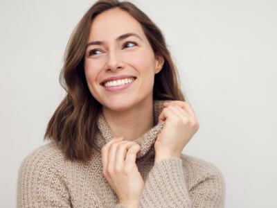 Smiling woman in beige sweater, embodying pre-operative health for surgery.