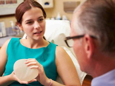 Young woman discussing about breast implants with her surgeon.